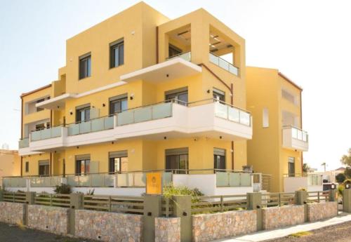 ein gelbes Gebäude mit einem Zaun davor in der Unterkunft Evriali Comfort Living in Palaiochóra