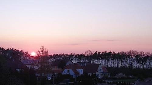 um pôr-do-sol sobre uma cidade com casas e árvores em Klif pokoje gościnne w centrum blisko morza em Ustronie Morskie