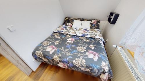 a small bedroom with a bed with a floral bedspread at Apartman Ateliér Vary v nově zrekonstruovaném domě in Karlovy Vary