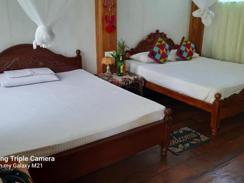 um quarto com 2 camas e uma mesa com uma mesa de cabeceira em Ruk Sewana Villa Tree House em Sigiriya