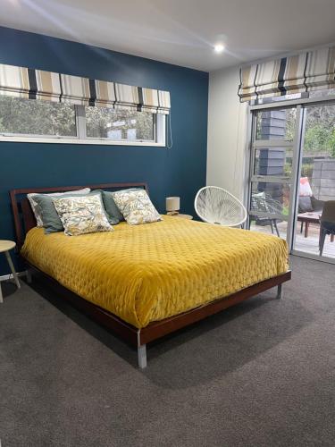 ein Schlafzimmer mit einem Bett mit einer gelben Decke in der Unterkunft Titoki Grove in Cambridge