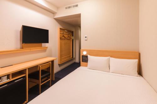 um quarto de hotel com uma cama e uma televisão em Sotetsu Fresa Inn Kamakura-Ofuna kasamaguchi em Kamakura
