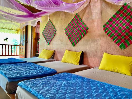 a room with three beds and a wall with kites at Du Gia Field View Homestay in Làng Cac