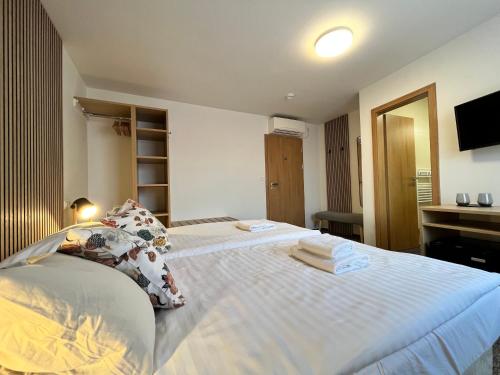 a bedroom with a large white bed with towels on it at Penzion U Halmů in Hustopeče