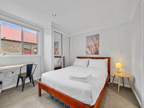 a bedroom with a bed and a desk and a window at Central Armidale 2-Bedroom Apartment in Armidale