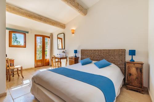 um quarto com uma cama grande e almofadas azuis em La Bastide de l'Oliveraie em Le Castellet