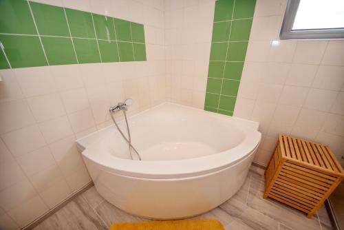 a bath tub in a bathroom with green and white tiles at Sara Sea View Apartments - ByChoice in Olimp