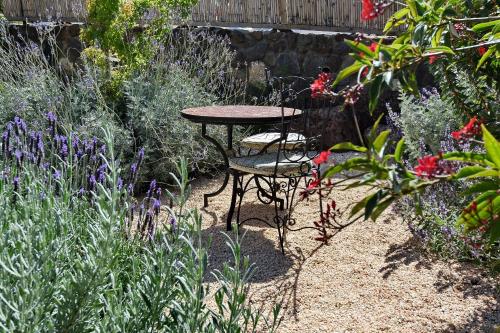 a table and chairs in a garden with flowers at וילה אלטה בוטיק - לנפוש בארץ להרגיש בחו"ל in Mishmār Hāyardin