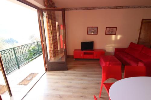 a living room with a red couch and a balcony at red house conditioned whit pool enchanting lake view in Malcesine