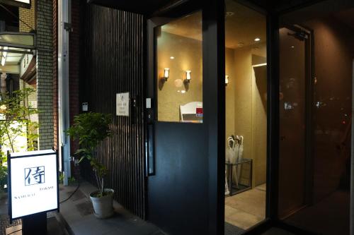 una puerta con una señal delante de un edificio en Guest House Tokyo Samurai en Tokio