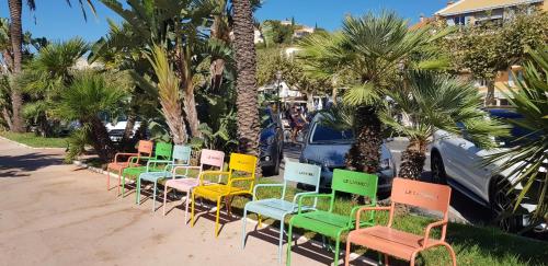 a row of chairs lined up on a sidewalk with palm trees at L'Odyssée provençale, un duplex de charme de 2 chambres au pied du village médiéval de Bormes-les-Mimosas, offrant des prestations haut de gamme et une superbe vue sur le Massif des Maures in Bormes-les-Mimosas