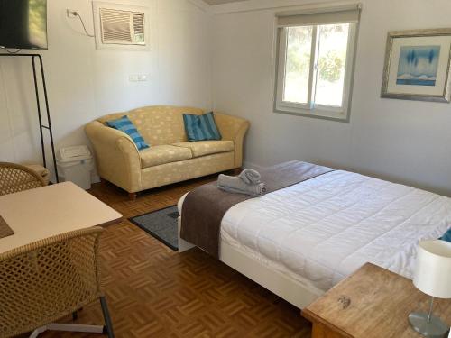 a small bedroom with a bed and a couch at Seaspray Beach Holiday Park in Dongara