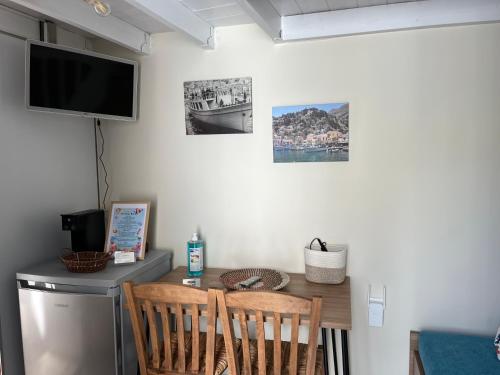 a dining room table with two chairs and a television at Aleminas Rooms in Symi