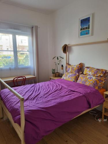 a bed with a purple comforter in a bedroom at Appartement contemporain jardin & jacuzzi in Voisins-le-Bretonneux