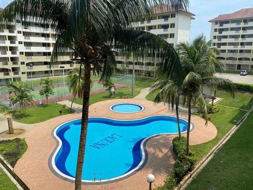 a swimming pool with palm trees in a resort at Colobeentoi Three Bedroom Sea View in Port Dickson