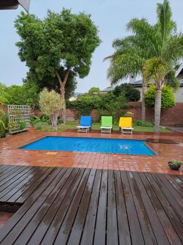 a patio with three chairs and a swimming pool at Plettenberg Bay 7 BUNKER AVENUE in Plettenberg Bay