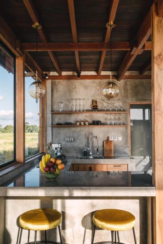 a kitchen with two stools and a counter with a sink at Beach 600M - Designer Villas - Perenenean - Private Pool in Canggu