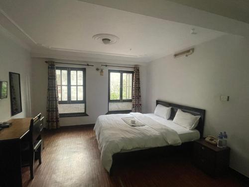 1 dormitorio con 1 cama, escritorio y 2 ventanas en Hotel Little Buddha Inn en Katmandú