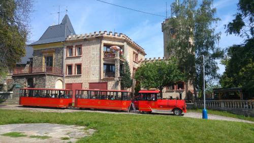 a red train is parked in front of a building at Penzion hrad Doubravka in Teplice