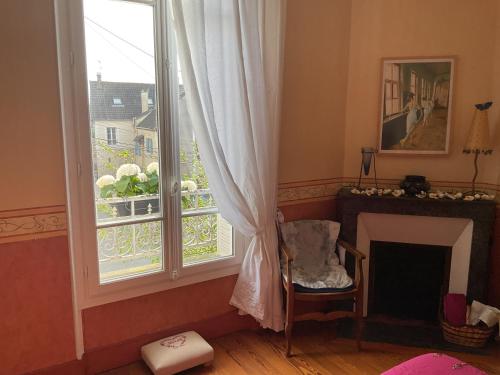 a living room with a large window and a fireplace at Atelier chez Marie in Carnetin