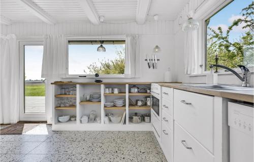 eine Küche mit weißen Schränken, einem Waschbecken und einem Fenster in der Unterkunft 2 Bedroom Amazing Home In Rudkbing in Illebølle