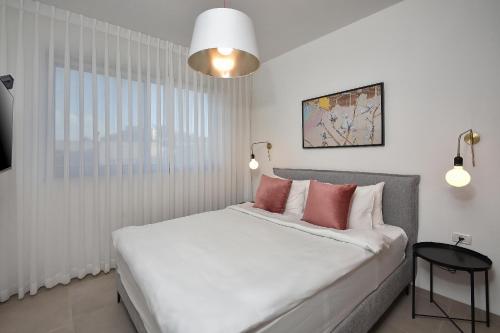 a bedroom with a large white bed with pink pillows at THE ALTA GALILEA - 3BRM WITH POOl in Mishmār Hāyardin