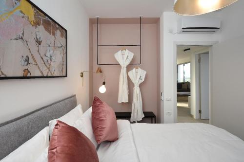 1 dormitorio con cama blanca y almohadas rojas en THE ALTA GALILEA - 3BRM WITH POOl, en Mishmār Hāyardin