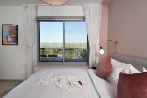 a bedroom with a bed with a large window at THE ALTA GALILEA - 3BRM WITH POOl in Mishmār Hāyardin