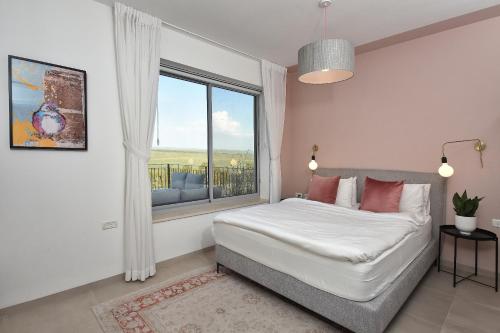 a bedroom with a bed and a large window at THE ALTA GALILEA - 3BRM WITH POOl in Mishmār Hāyardin