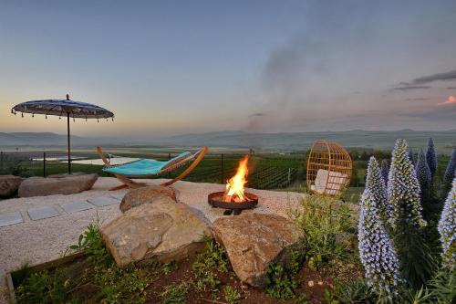 a fire pit with chairs and an umbrella and a table at THE ALTA GALILEA - 3BRM WITH POOl in Mishmār Hāyardin