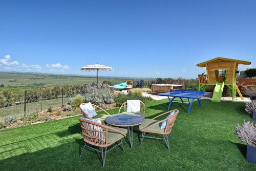 a patio with a table and chairs on the grass at THE ALTA GALILEA - 3BRM WITH POOl in Mishmār Hāyardin