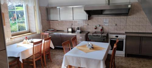 eine Küche mit 2 Tischen, Stühlen und einem Herd in der Unterkunft Wpadnij do Zosi - ex Pensjonat Emilia in Stronie Śląskie