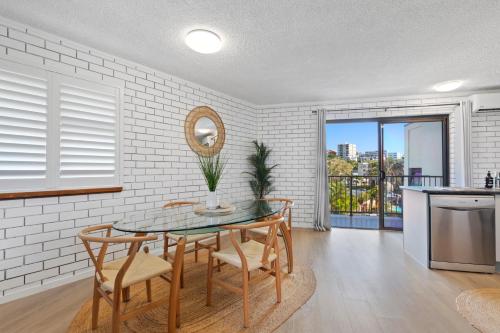 a dining room with a table and chairs and a kitchen at Ashwood on Kings- Kings Beach in Caloundra