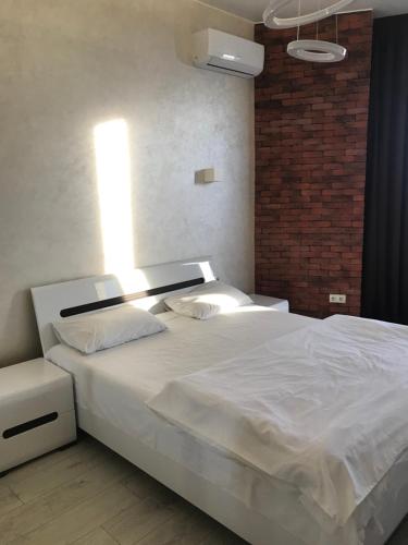 a bedroom with a white bed with a brick wall at Apart Plaza 24 in Kyiv