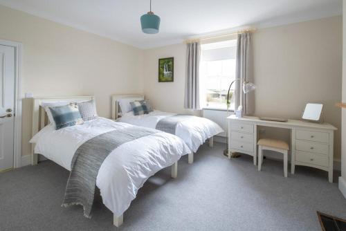 a bedroom with two beds and a desk and a window at Church Farmhouse - Castle View (4 bedroom) & Church View (2 bedroom) in Castletown