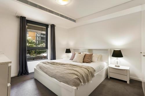 a white bedroom with a bed and a window at Stylish 1 bdrm Camperdown - Car park, Gym & Pool in Sydney