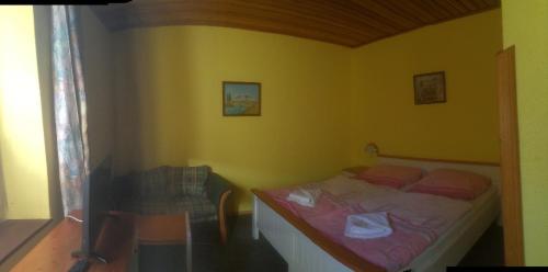 1 dormitorio con 1 cama en una pared amarilla en Penzion u Příhodů, en Jesenice
