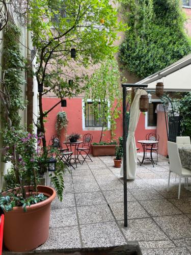 Hotel Apostoli Garden في البندقية: فناء في الهواء الطلق مع طاولات وكراسي ونباتات