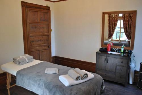 a bedroom with a bed and a dresser and a mirror at Eta's Manor @ Brooklands in Maryport