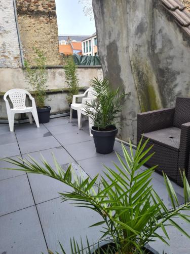 a patio with chairs and potted plants on a building at L'appart Audomarois in Saint-Omer