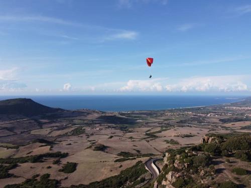 a kite flying in the sky over the ocean at Casa Su Soli Sardu 10 - Mit Blick aufs Meer! in La Ciaccia