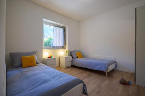 een slaapkamer met 2 bedden en een raam bij Residence Girasole Casa Rossa B in Colico