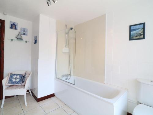 a white bathroom with a tub and a chair at The Corn Tallet in Bideford