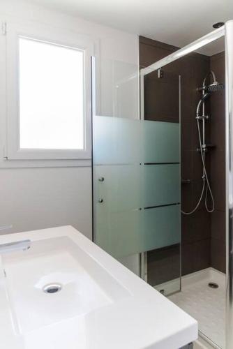 une salle de bain avec un lavabo blanc et une douche dans l'établissement Villa 4 personnes U Pinu, piscine partagée, 6 kms de porto vecchio, à Porto-Vecchio