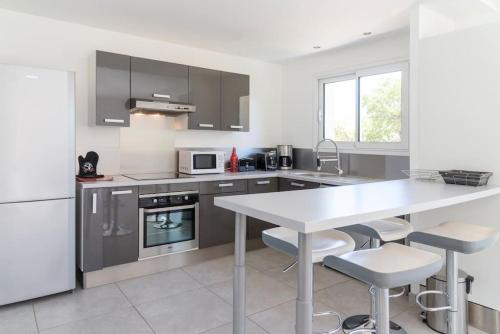 une cuisine blanche avec une table et des chaises blanches dans l'établissement Villa 4 personnes U Pinu, piscine partagée, 6 kms de porto vecchio, à Porto-Vecchio