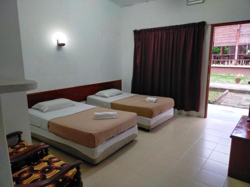 two beds in a room with a window at Seri Indah Resort in Kuala Terengganu