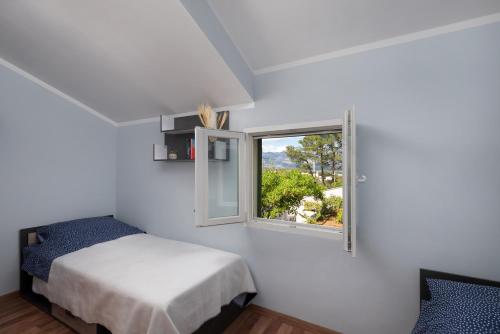 a white bedroom with a bed and a window at Green House in Novigrad Dalmatia
