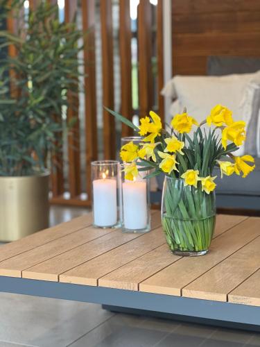 a table with a vase of yellow flowers and candles at Villa Gorczański Zakątek Agroturystyka in Konina