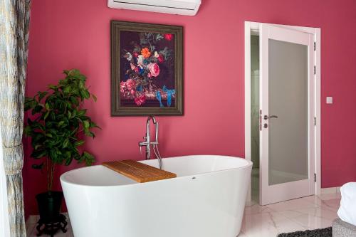 a bath tub in a bathroom with a pink wall at 100 Boutique Living in Rabat