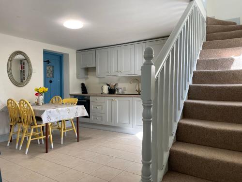 een keuken en eetkamer met een tafel en een trap bij Mai's Cottage Suite - Charming Holiday Rental in Kilmallock